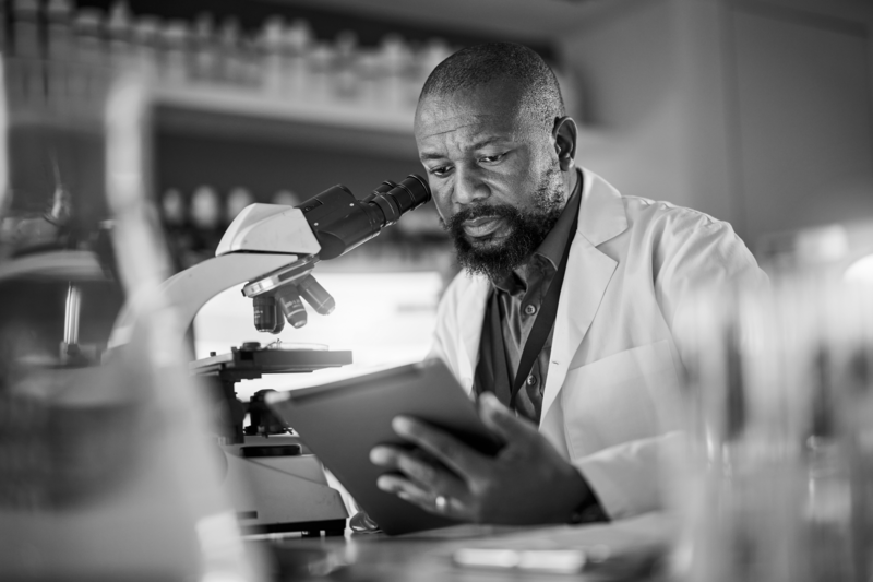SINGLE-IMAGE_black-man-pharmacist-with-microscope_aug24